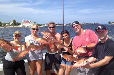 group of people hold red snapper fish